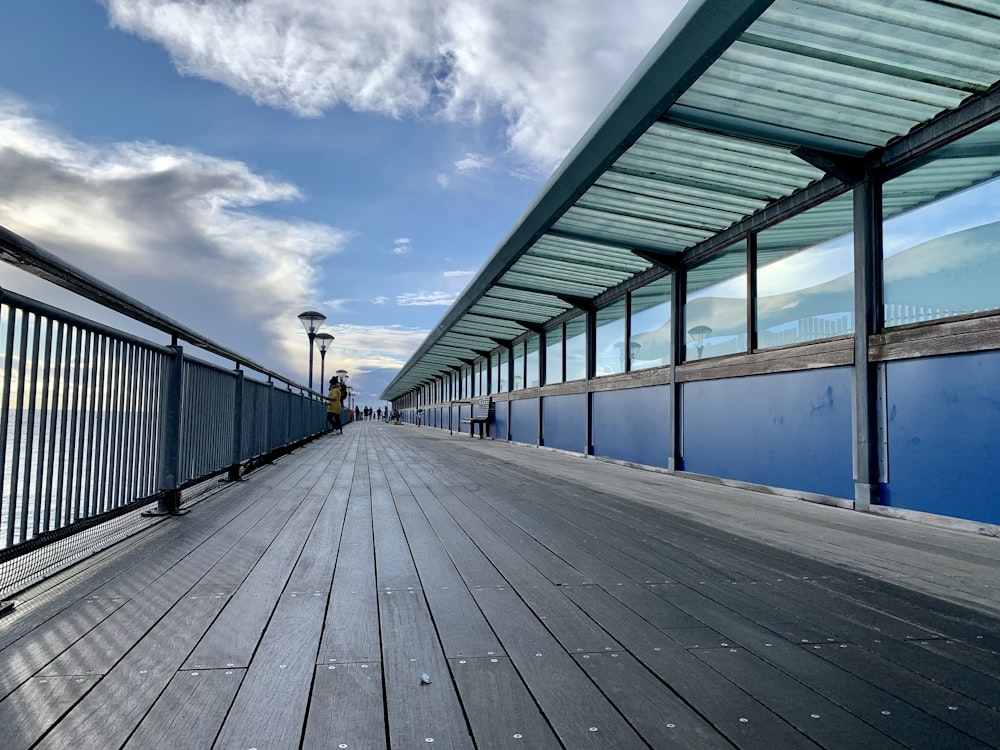 person in black jacket walking on gray wooden dock during daytime