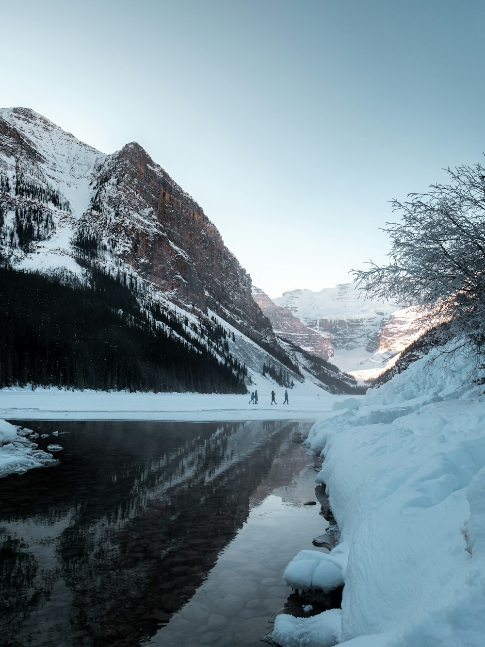 body of water near snow covered mountain during daytime