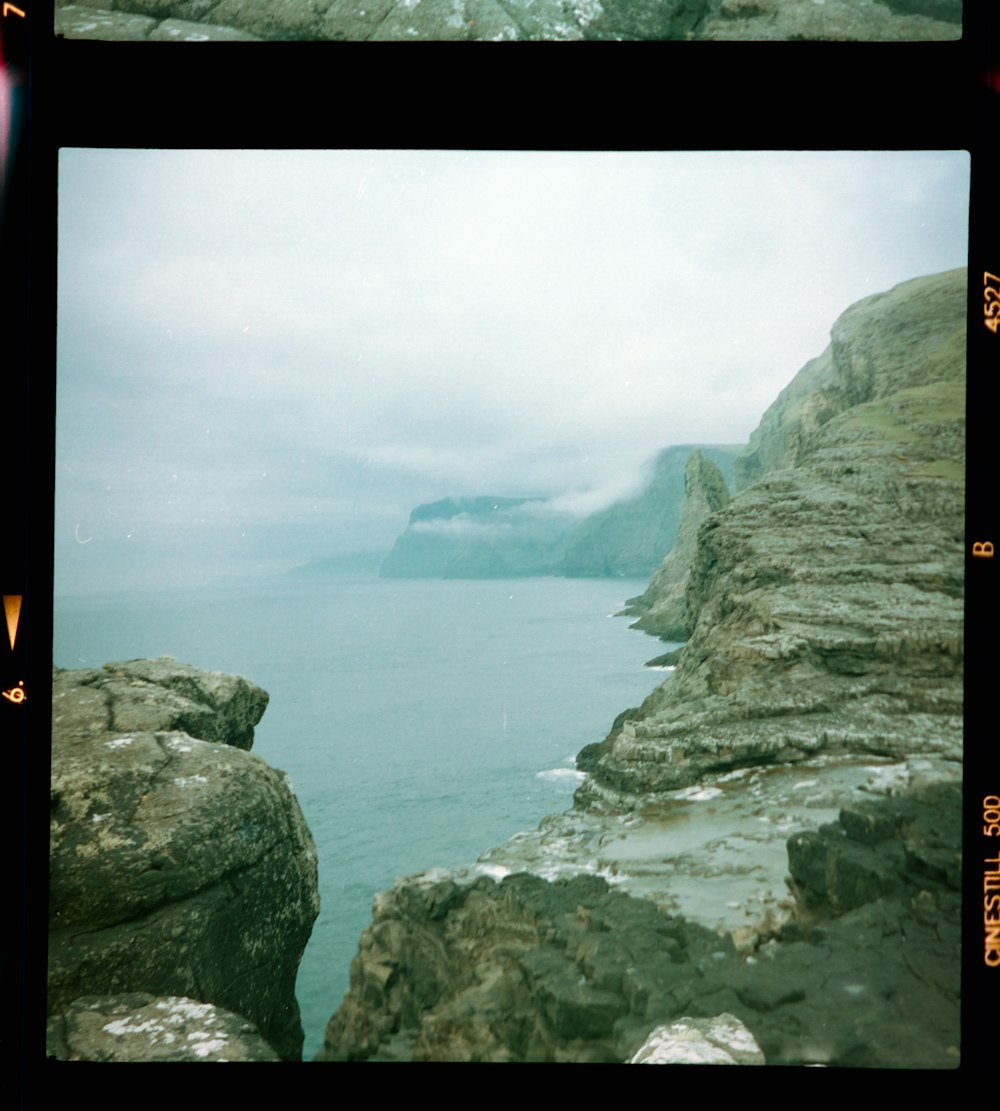 gray rocky mountain beside sea during daytime