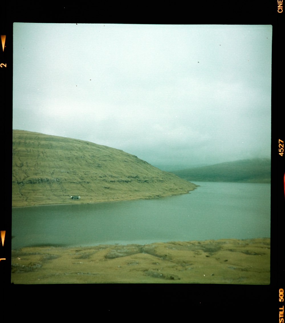 green mountain beside body of water