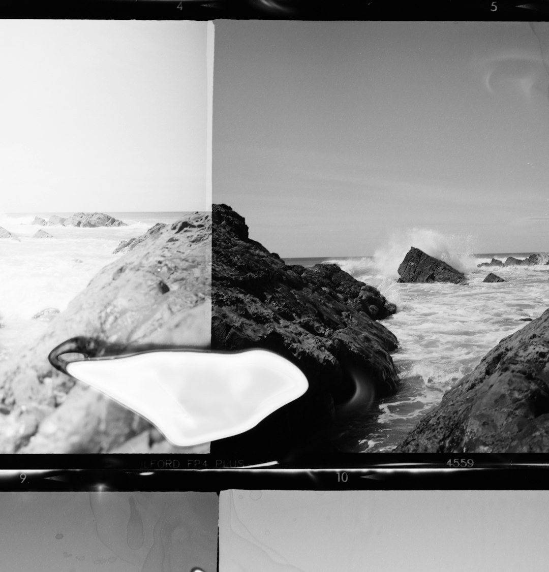 grayscale photo of rock formation on body of water