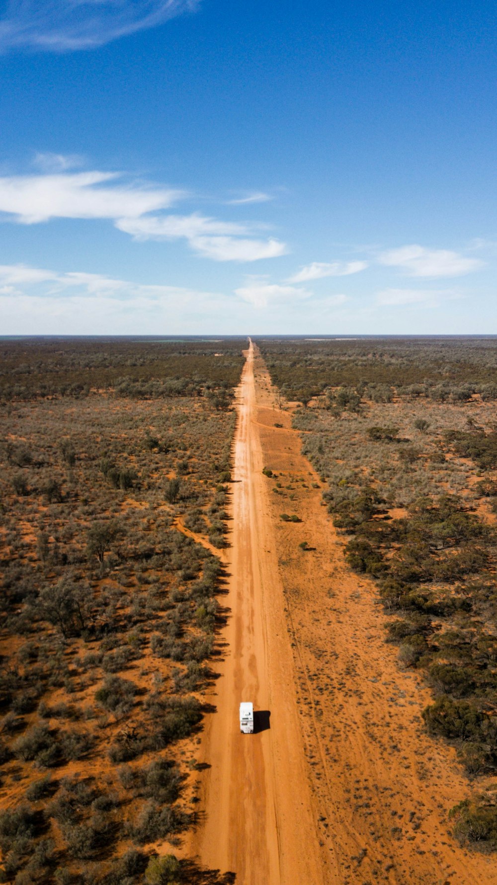 Camino de tierra marrón entre el campo de hierba verde bajo el cielo azul durante el día