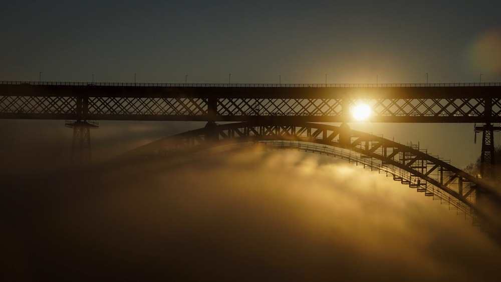 black metal bridge over body of water during sunset