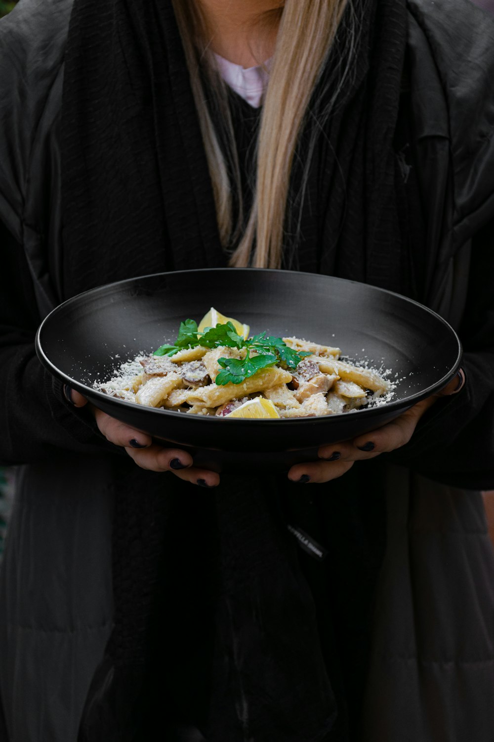 woman in black jacket holding black bowl with vegetable salad