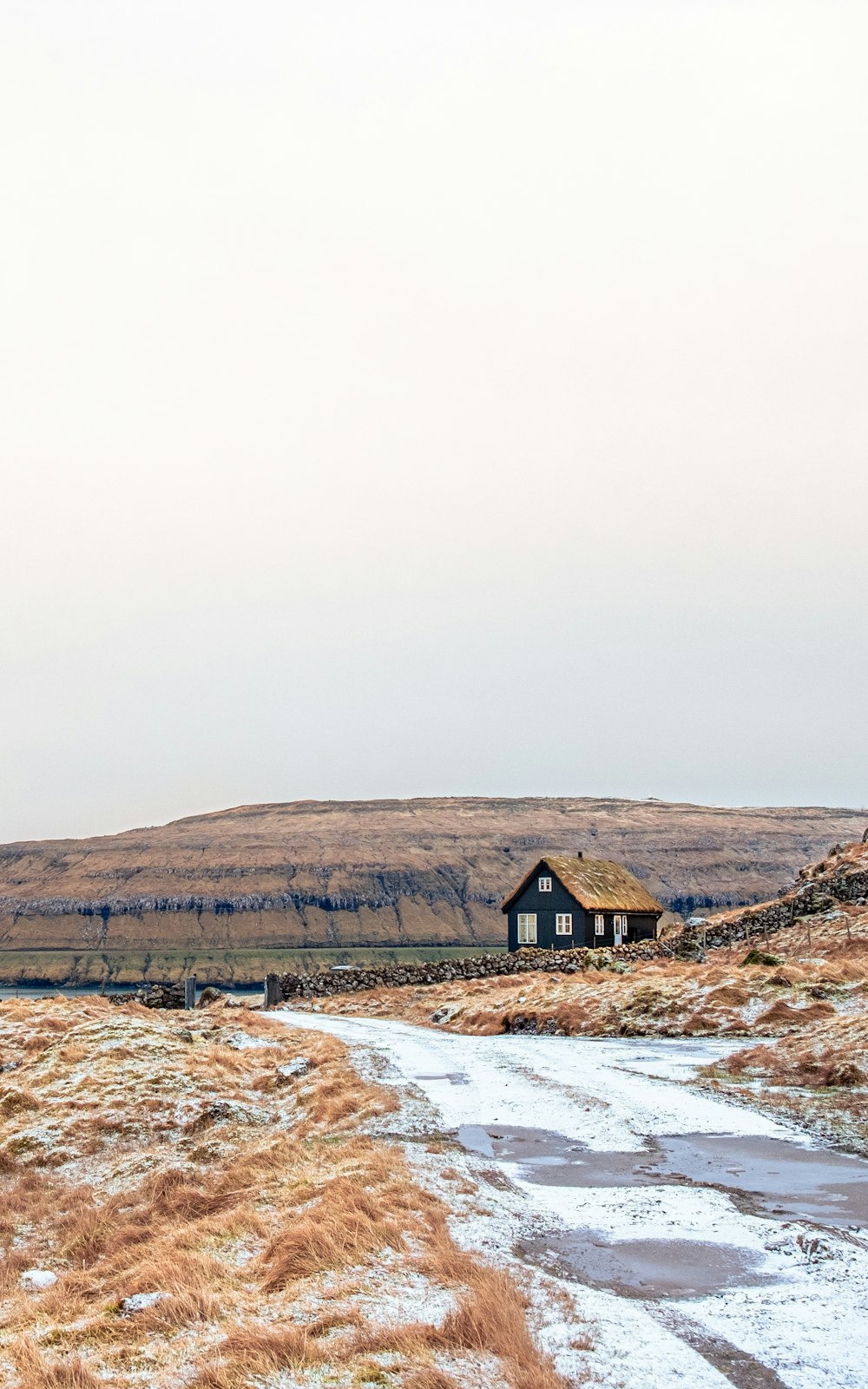 casa de madera marrón en campo marrón bajo el cielo blanco durante el día