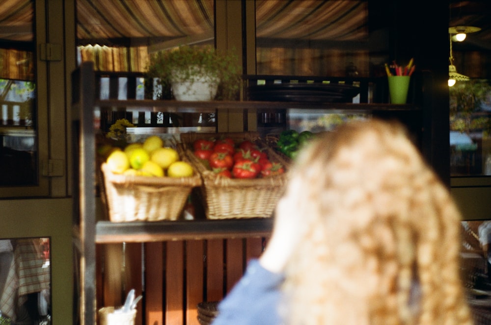 pessoa em jeans azuis em pé perto da banca de frutas