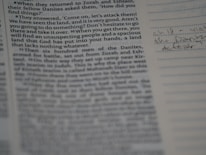 Close-up of hands writing in a journal with scripture and historical texts nearby.