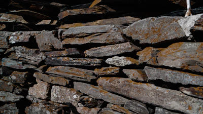 Close-up of skilled mason working on stone wall with traditional tools.
