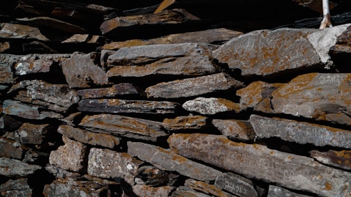A close-up view of a traditional stone wall constructed with irregular, moss-covered stones, stacked meticulously with visible textures and natural weathering.