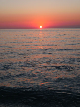 Sunset over a calm ocean with warm golden and deep blue tones.