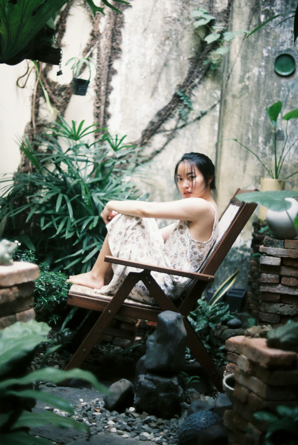 woman in white floral sleeveless dress sitting on brown wooden chair