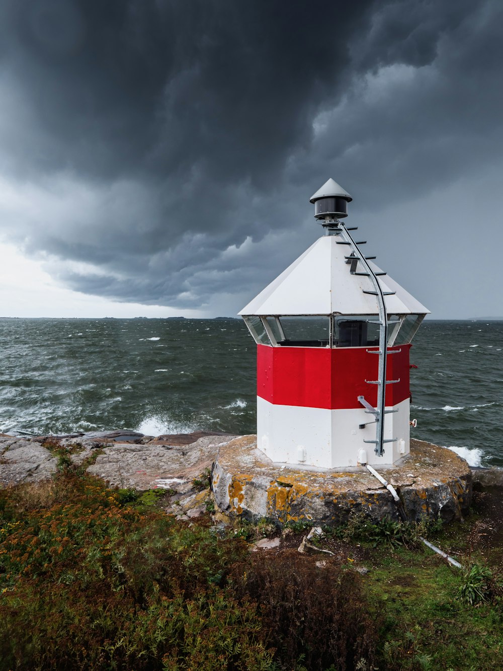 white and red lighthouse near body of water under cloudy sky during daytime
