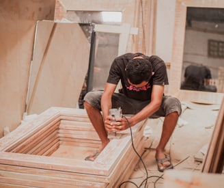 man in black t-shirt and black shorts sitting on brown wooden stairs