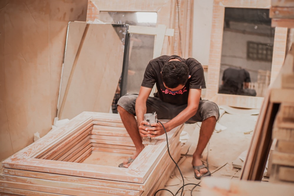 man in black t-shirt and black shorts sitting on brown wooden stairs