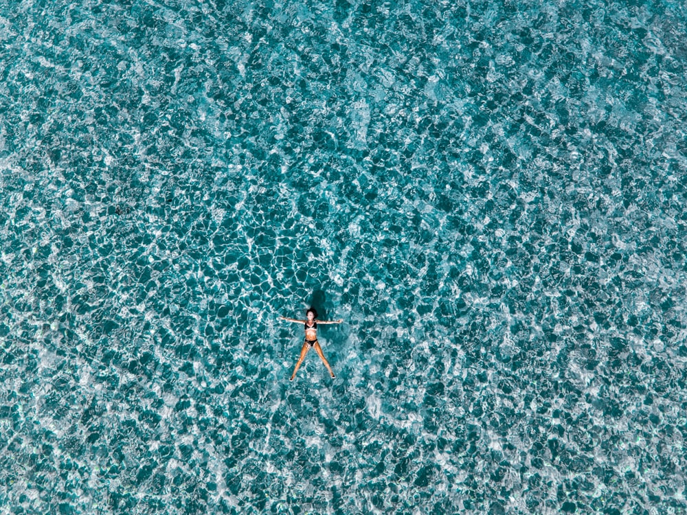 person in black and red shorts on body of water during daytime