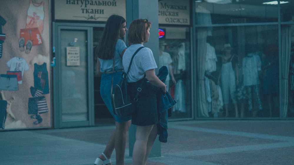 2 women walking on sidewalk during daytime