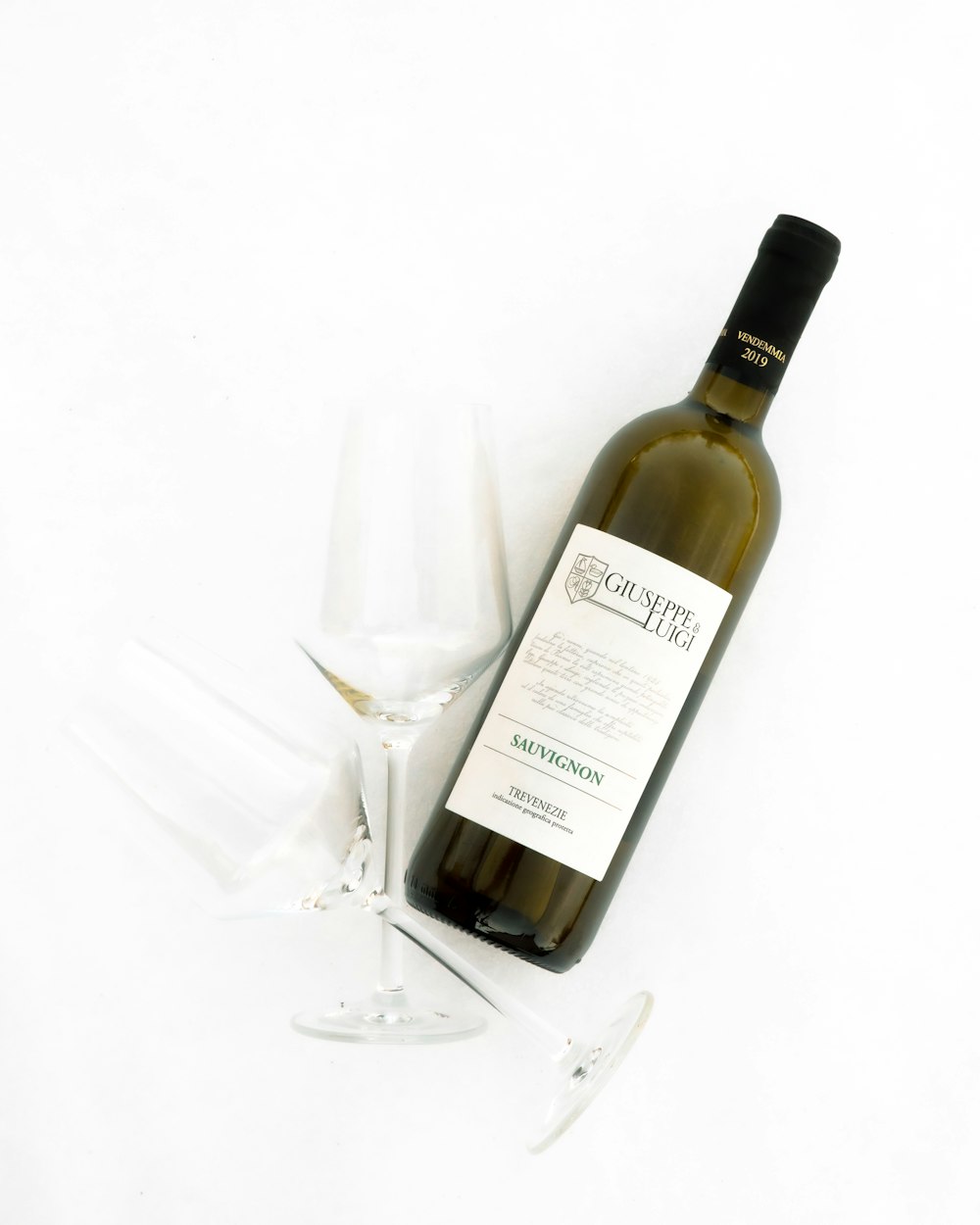 white labeled bottle beside clear wine glass