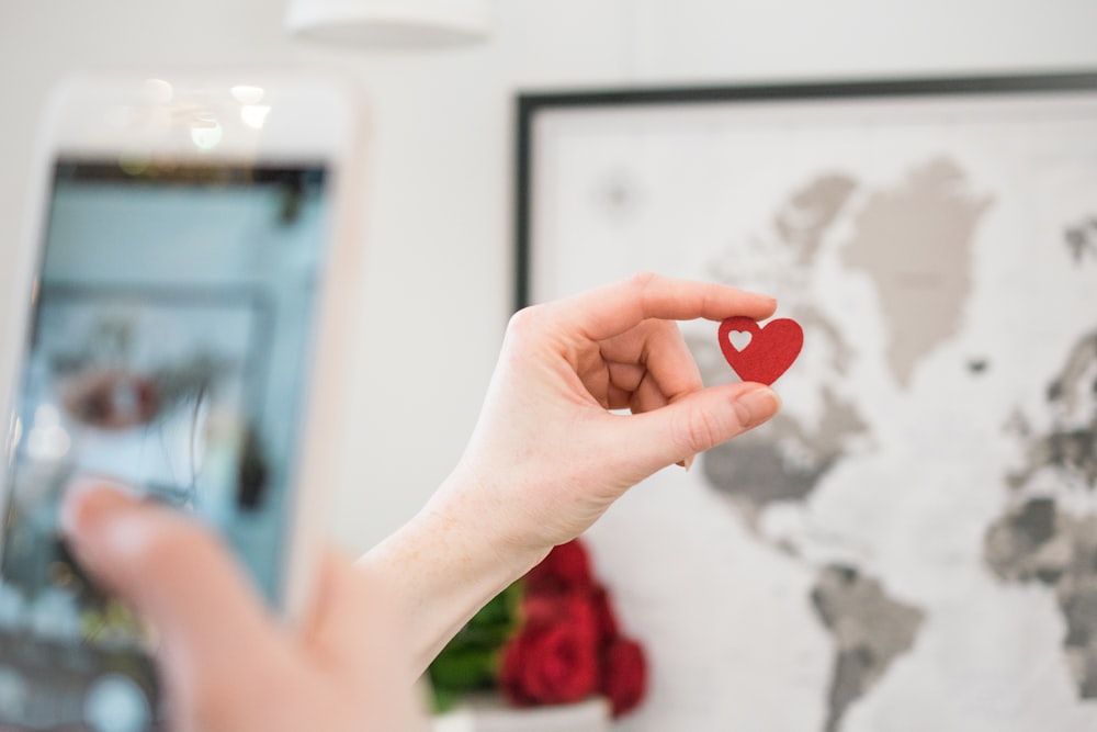 person holding red heart ornament