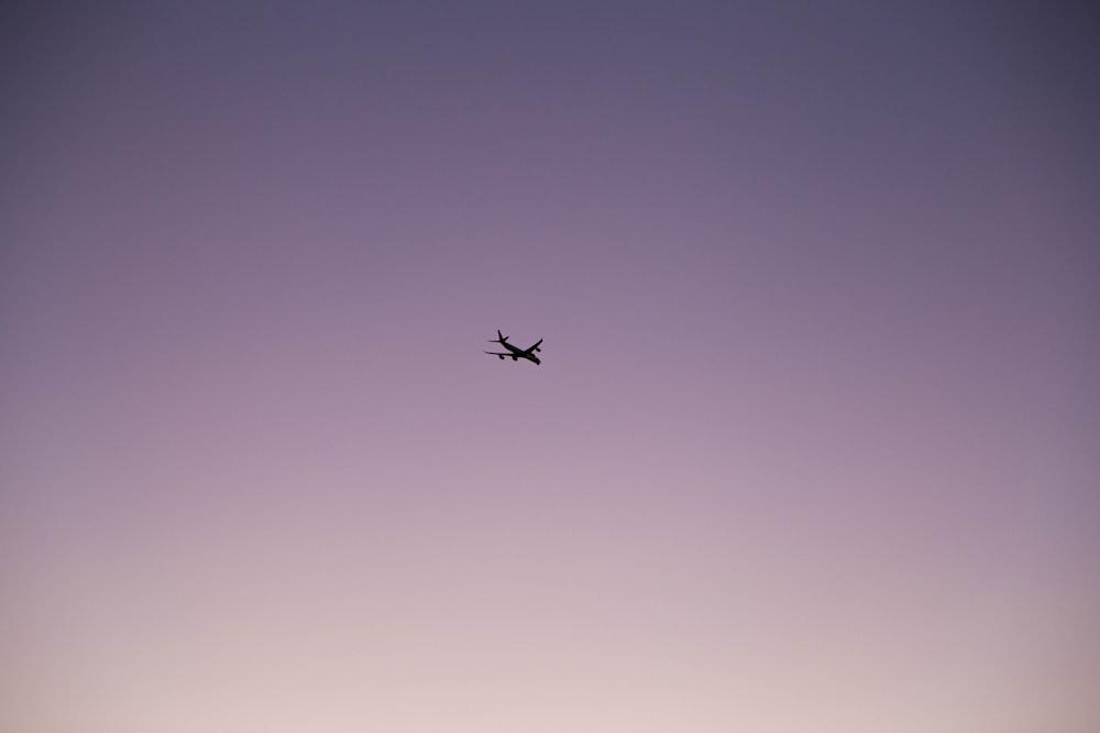 an airplane flying in the sky at dusk