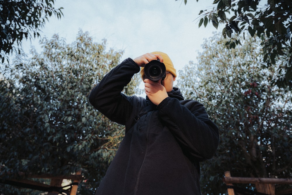 man in black jacket holding black camera