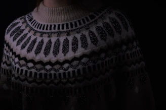 Close-up of a cozy hand-knit woolen sweater draped over a wooden chair.