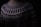 A close-up of a knitted sweater with intricate geometric patterns in black and white. The sweater has a high neckline and showcases various zigzag and dot designs. The lighting is dim, creating a cozy and warm atmosphere.