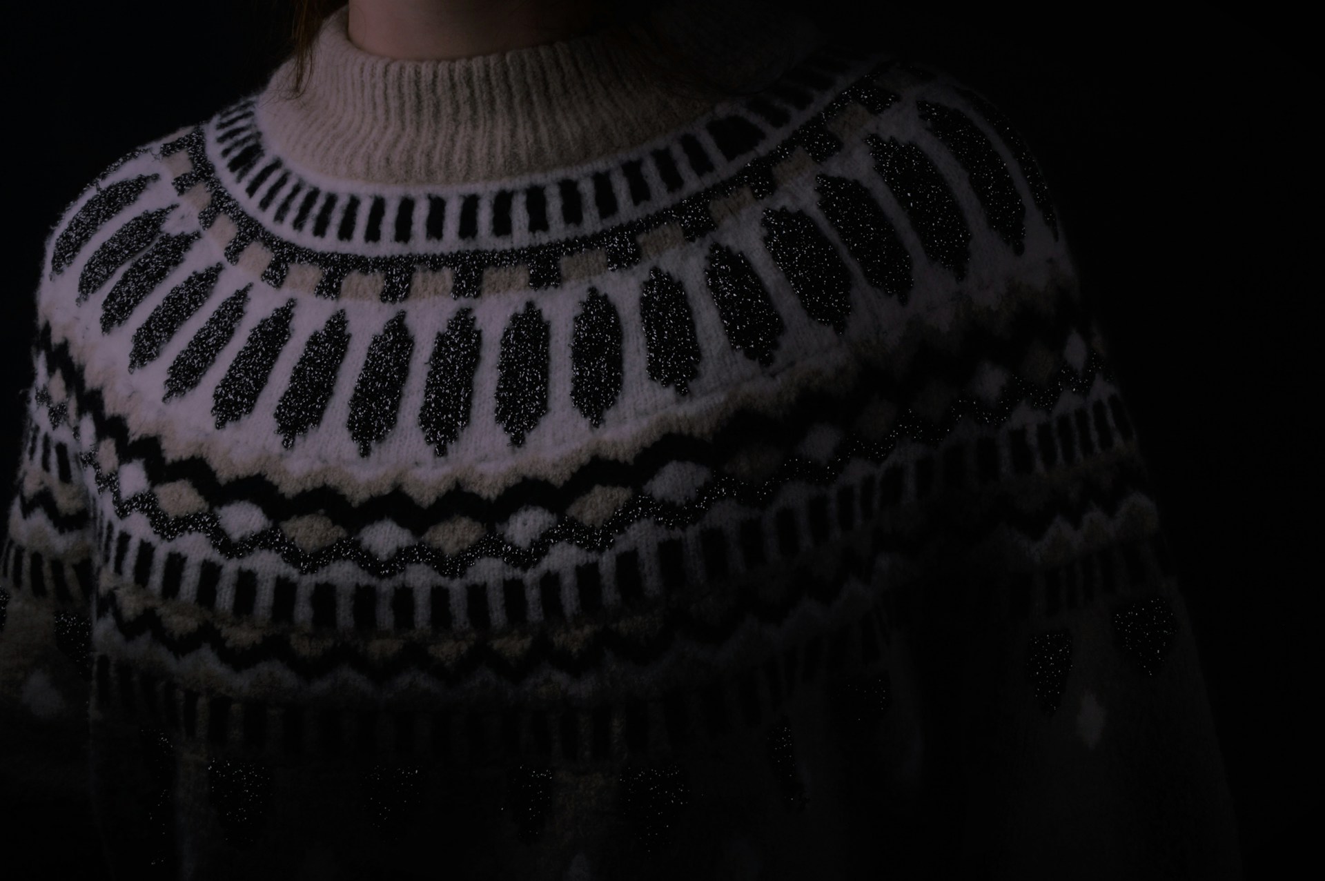 Close-up photo of a cozy, hand-knitted sweater showcasing intricate stitch patterns and warm, earthy tones.