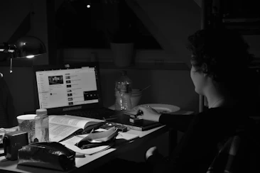 A focused student preparing personal essays with a laptop and notes in a cozy, bright study space.