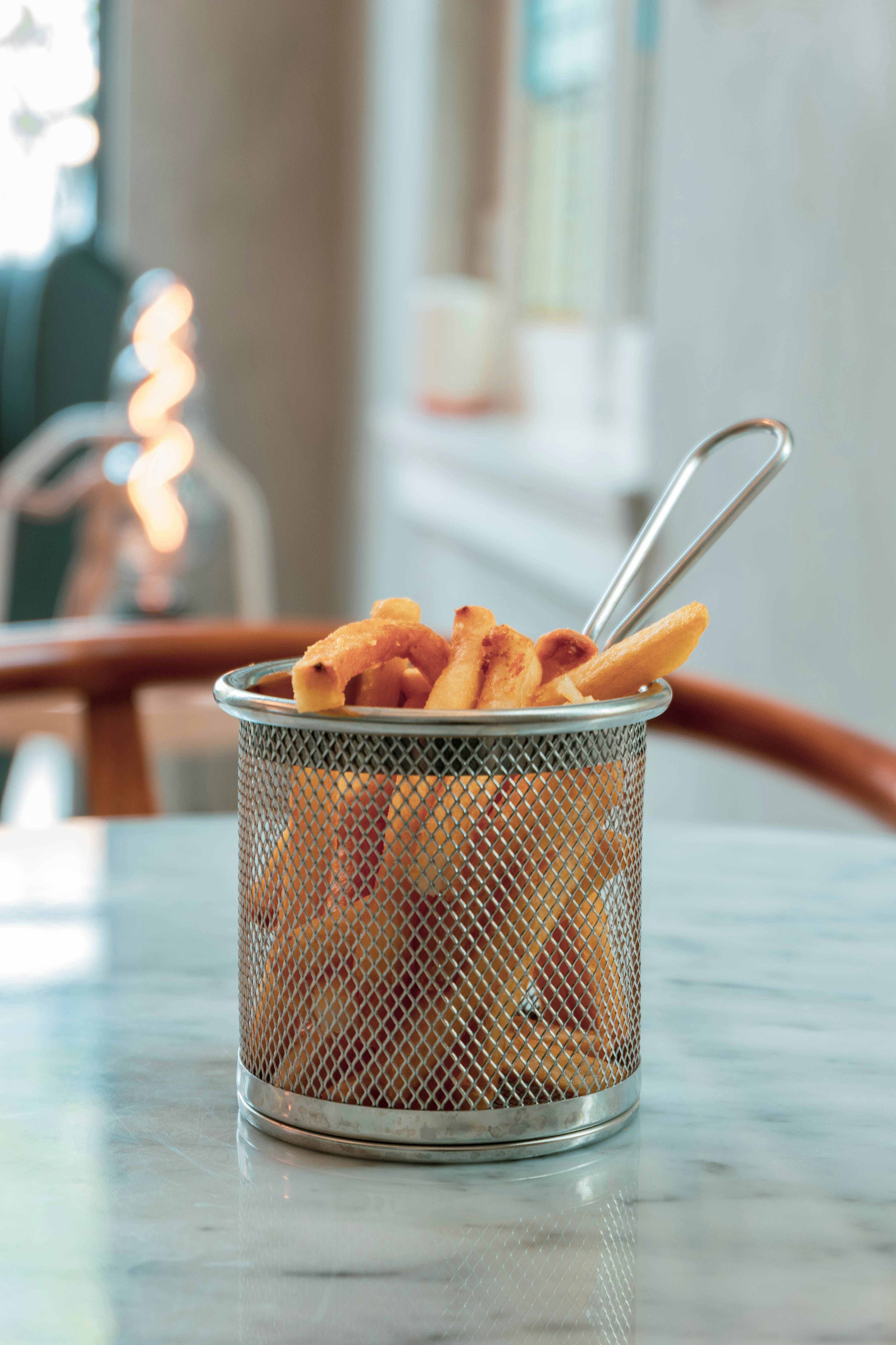 Golden truffle fries with parmesan shavings in a red basket, warm lighting
