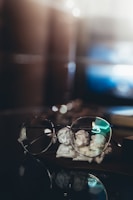 silver framed eyeglasses on brown wooden table