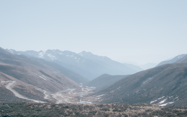 A panoramic view of a serene mountain valley with scattered homes and winding roads.