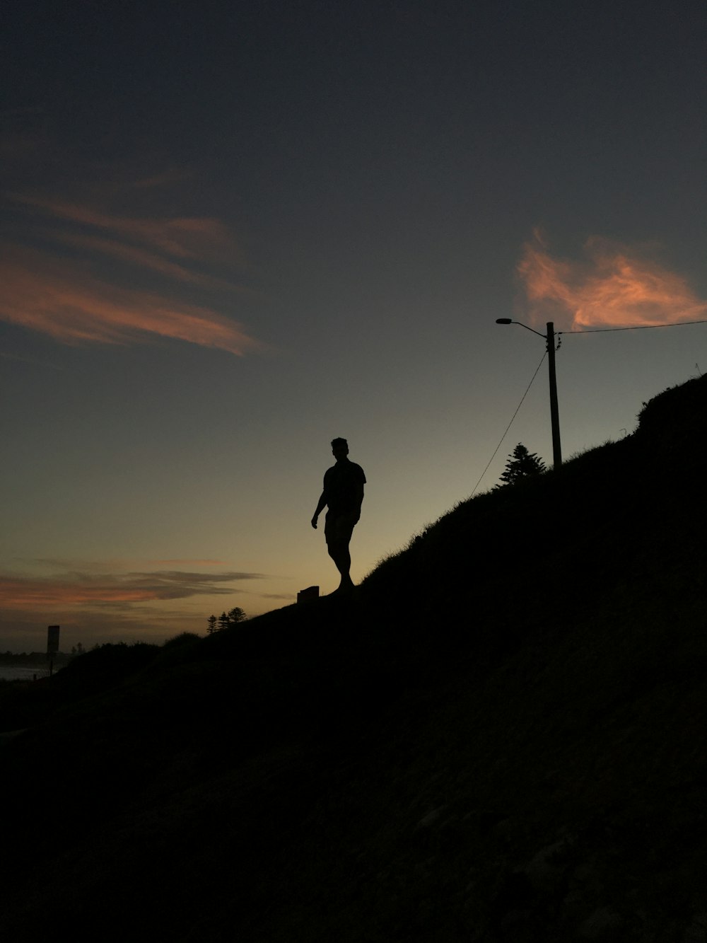 Silhouette eines Mannes, der bei Sonnenuntergang auf einem Hügel steht