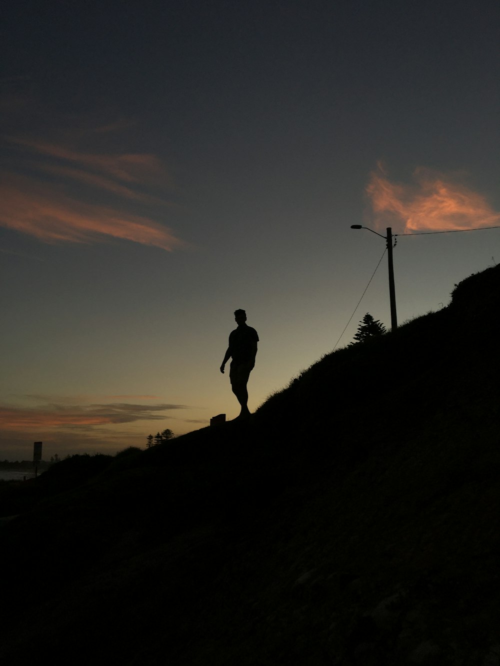 silhueta do homem de pé na colina durante o pôr do sol