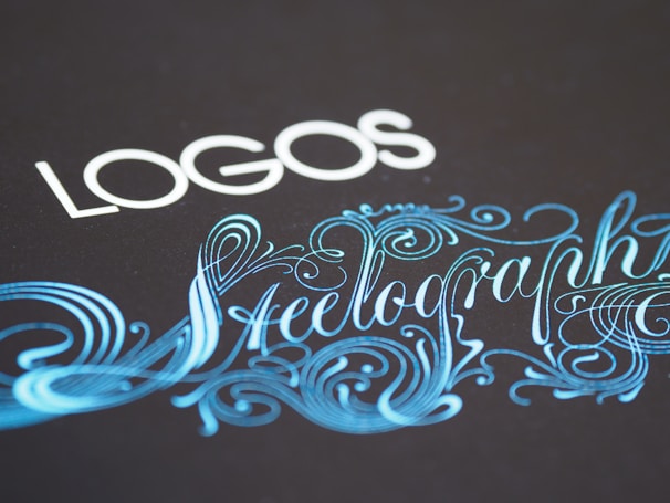 Elegant typography featuring the word 'LOGOS' in white capital letters, paired with an ornate script of 'Steelography' in a flowing, decorative blue font against a dark background.
