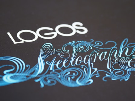 Elegant typography featuring the word 'LOGOS' in white capital letters, paired with an ornate script of 'Steelography' in a flowing, decorative blue font against a dark background.