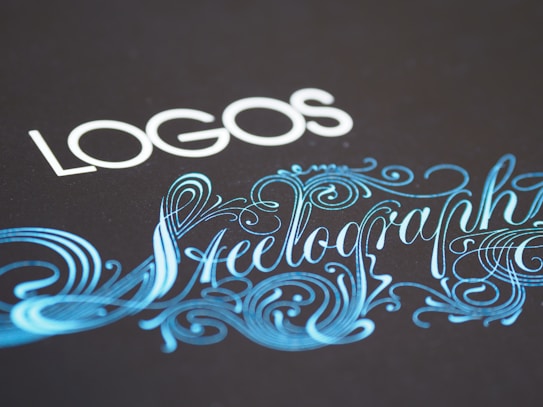 Elegant typography featuring the word 'LOGOS' in white capital letters, paired with an ornate script of 'Steelography' in a flowing, decorative blue font against a dark background.