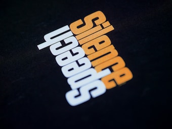 Text design featuring the word 'silence' in orange and 'speech' in white, with an inverted capital letter format against a black background.