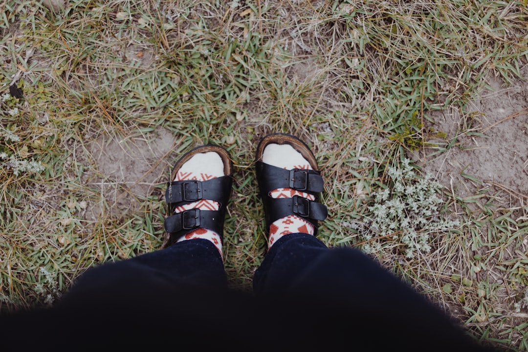 person wearing black pants and brown leather sandals