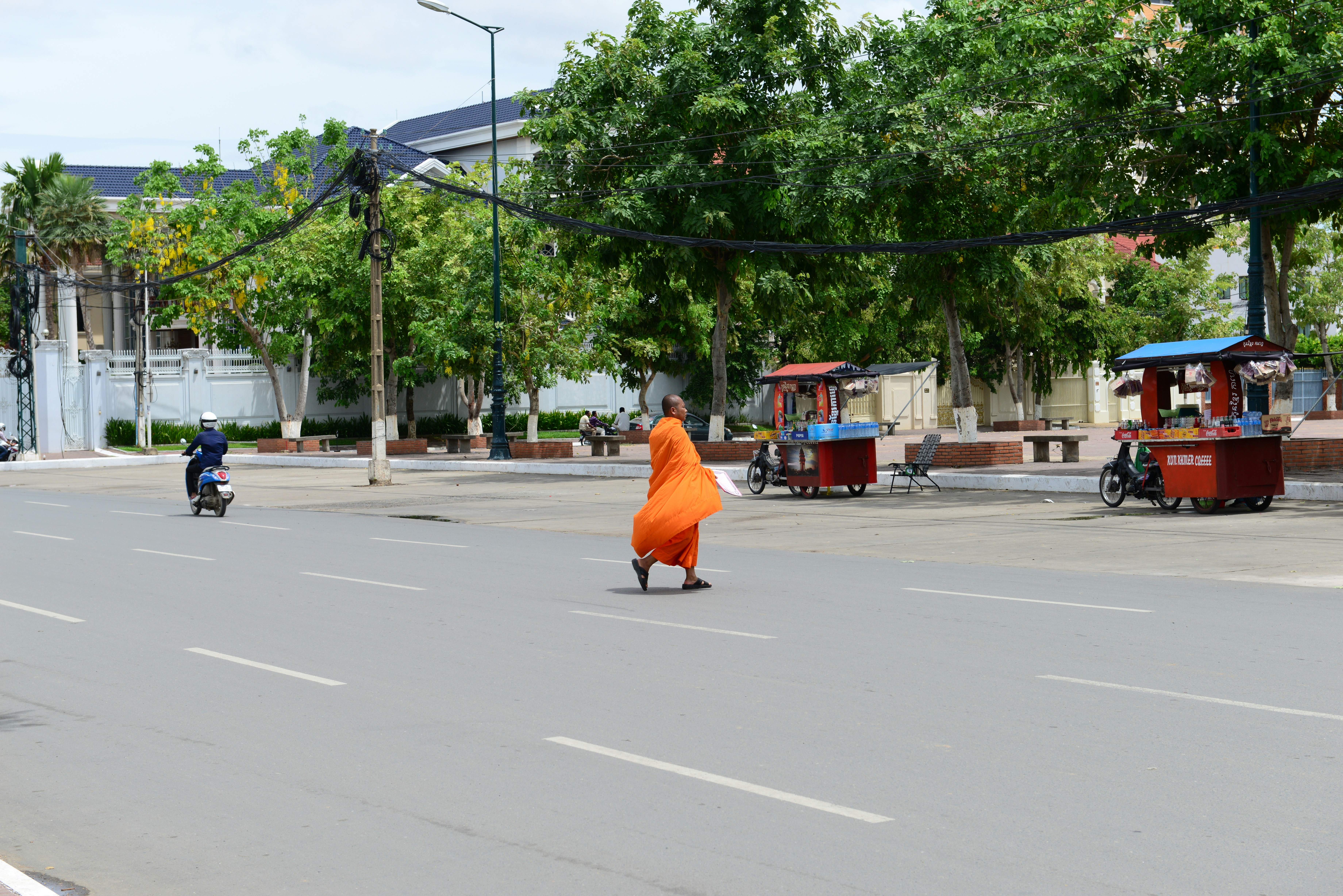 person in orange robe sitting on gray concrete road during daytime