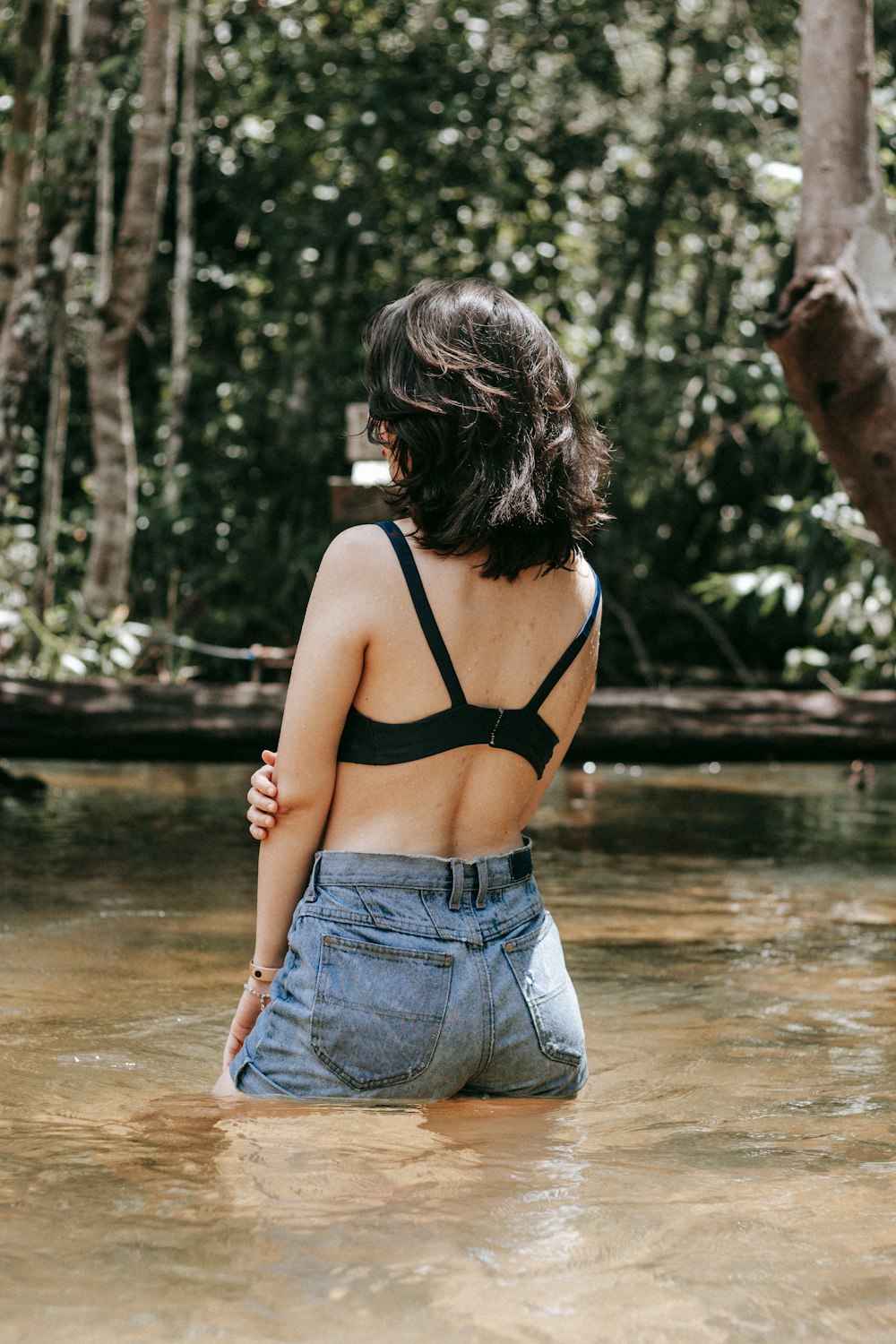 woman in black tank top and blue denim jeans standing on water