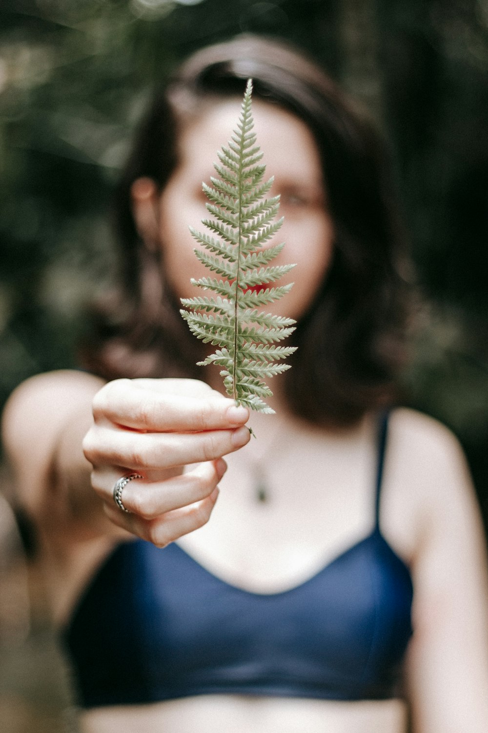 woman in blue tank top holding green plant