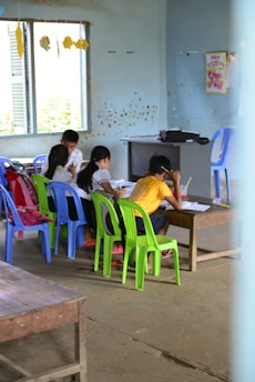 A group of smiling children studying together in a modest classroom.