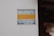 A sign is affixed to a white wall with the text 'MAXISAFE ARMED RESPONSE' in bold letters. The sign also contains a phone number 'Tel: 041 922 0324' at the bottom. The colors used in the sign are blue for 'MAXISAFE' and the phone number, and yellow for 'ARMED RESPONSE'. The right side of the image shows part of a brick structure, likely part of a building.