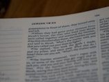 A close-up view of an open book, showing a passage from the Bible, specifically from the book of Judges. The focus is on the text, with sentences and verse numbers clearly visible. The lighting creates a gentle shadow over the page.