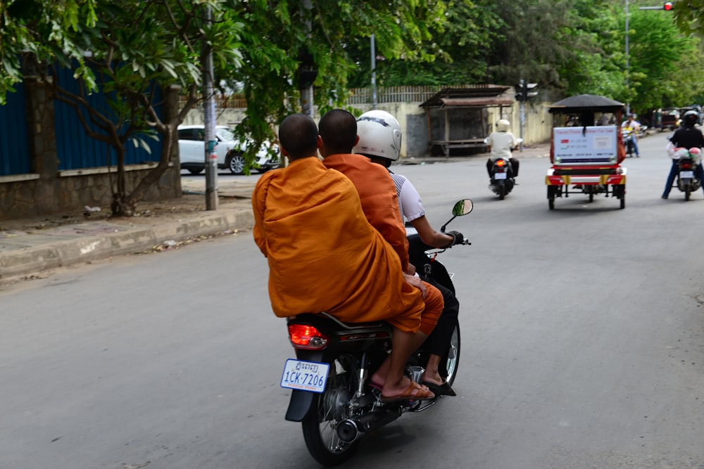 man in orange jacket riding on red motorcycle during daytime