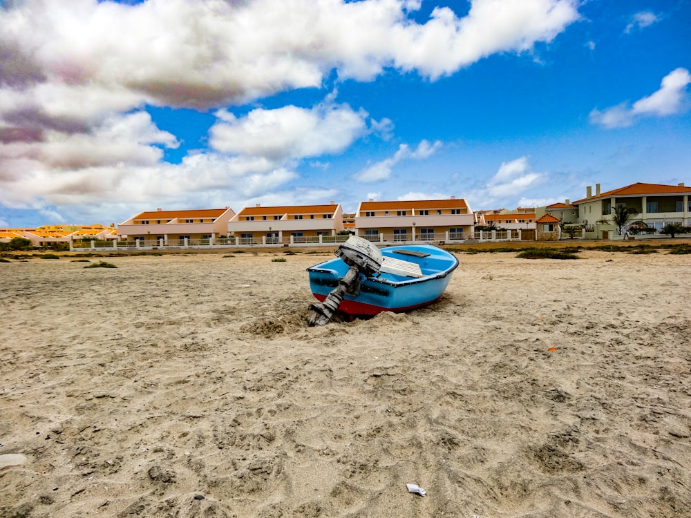 blue and white boat on brown sand under blue sky during daytime