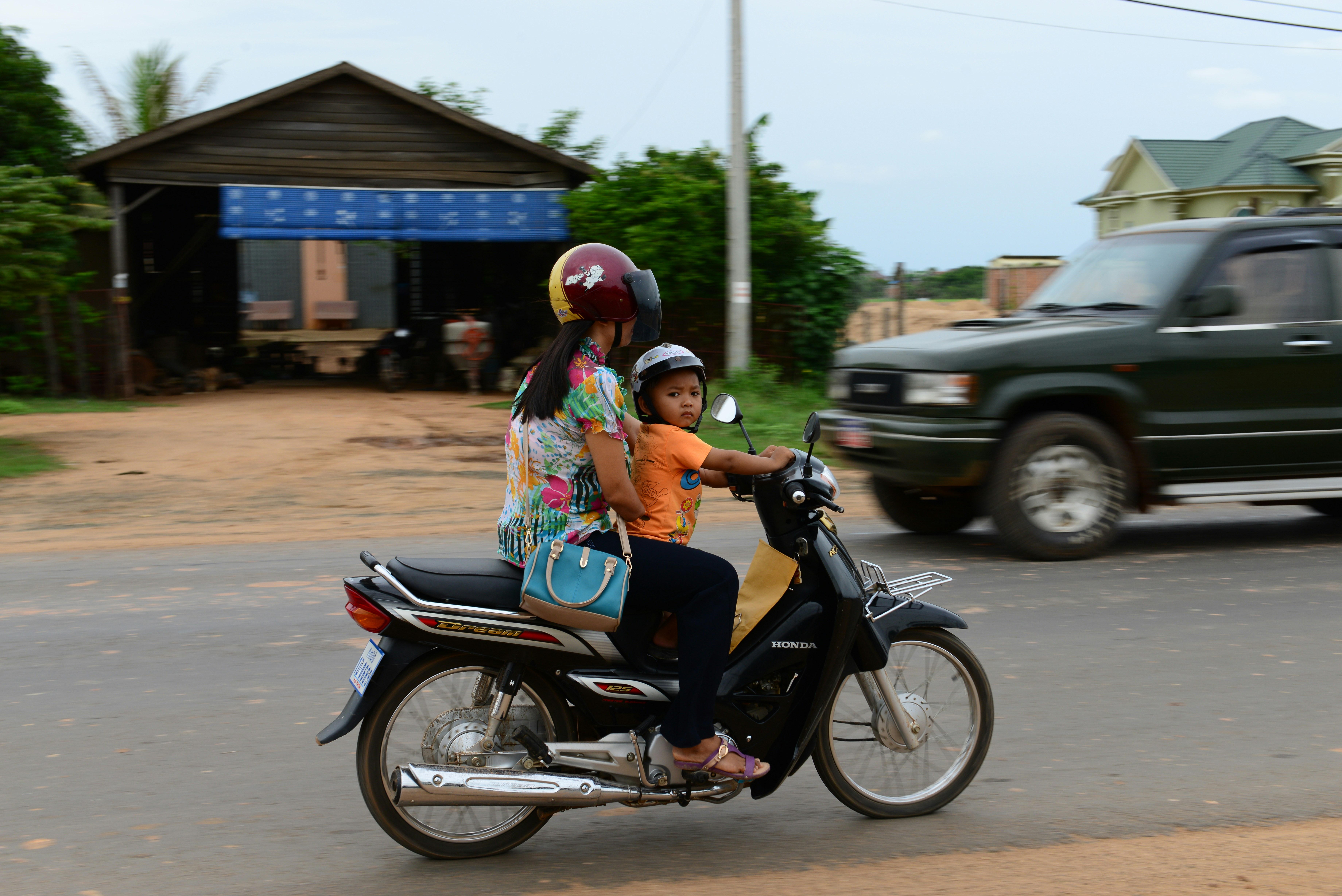 woman in blue and white floral dress riding on black motorcycle during daytime