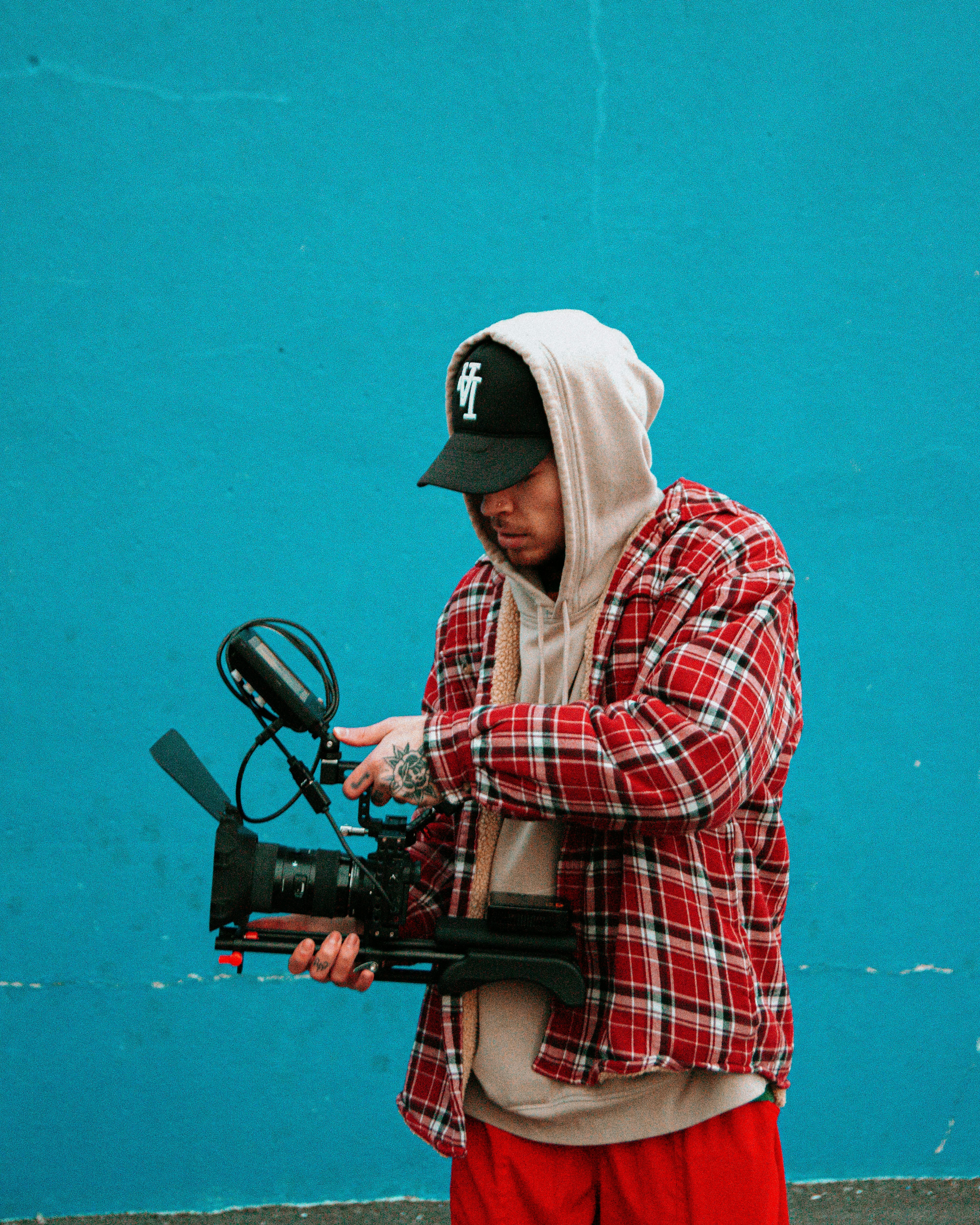 man in red white and blue plaid dress shirt and white hat holding black and red