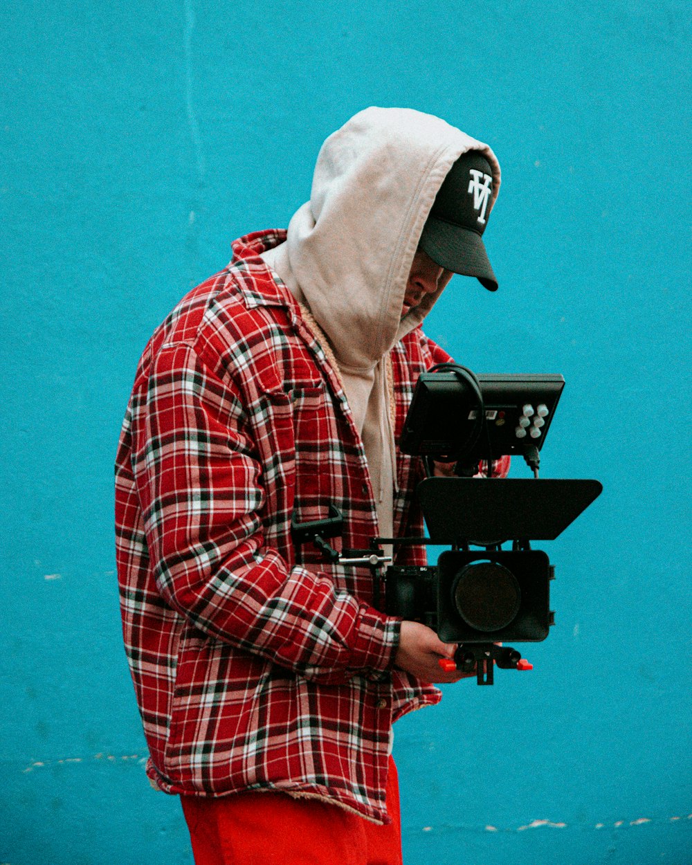 man in red white and black plaid dress shirt holding black dslr camera