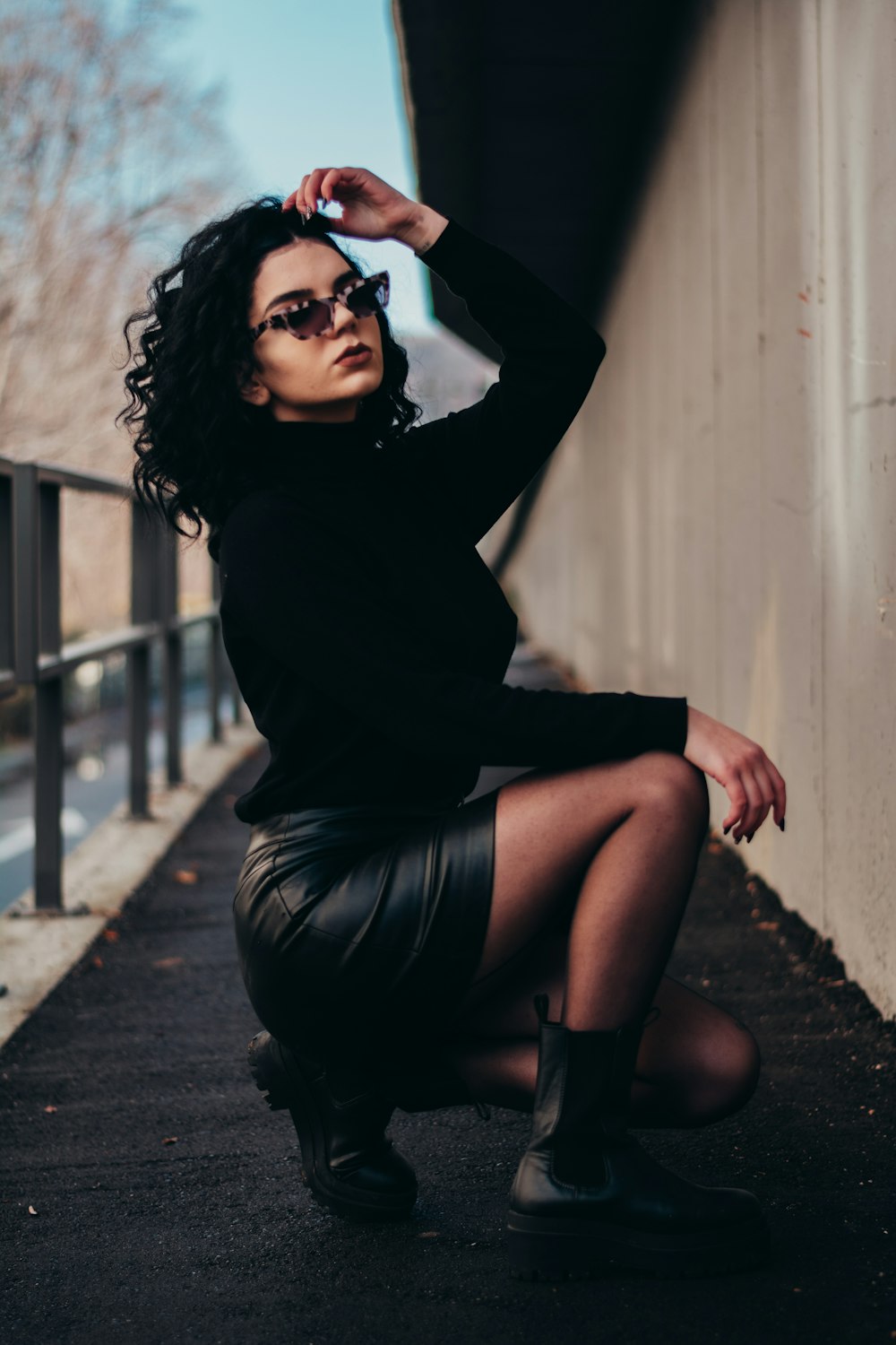 woman in black long sleeve shirt and black skirt sitting on brown wooden floor